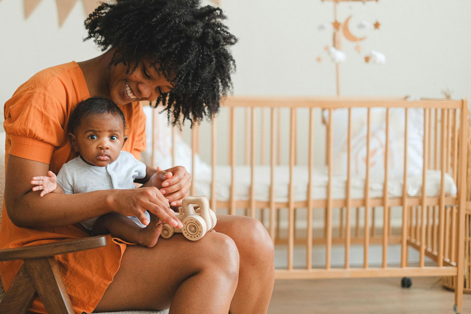 Joyful mother and her baby enjoy playtime in a cozy nursery setting, creating a warm family moment.